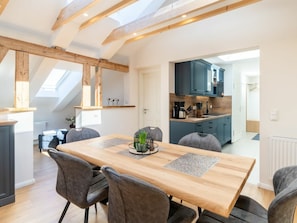 A modern kitchen with dark blue cabinets, a wooden dining table with grey placemats, and a skylight above. - Holiday Apartment With 1 Bedroom (Heringsdorf)