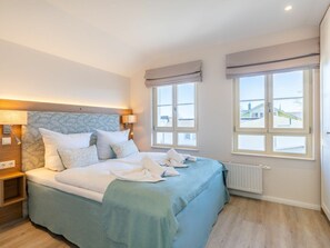 A bedroom with a bed, bedside lamps, a window, and a radiator. - Holiday Apartment With 1 Bedroom (Heringsdorf)