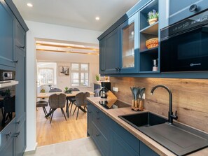 A modern kitchen with dark blue cabinets, a wooden countertop, and a built-in oven. - Holiday Apartment With 1 Bedroom (Heringsdorf)