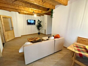 A living room with a sofa, a television, a potted plant, and a wooden ceiling. - Holiday Apartment With 1 Bedroom (Zirchow)