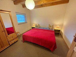 A bedroom with a bed, a wooden wardrobe, a window, and a lamp. - Holiday Apartment With 1 Bedroom (Zirchow)