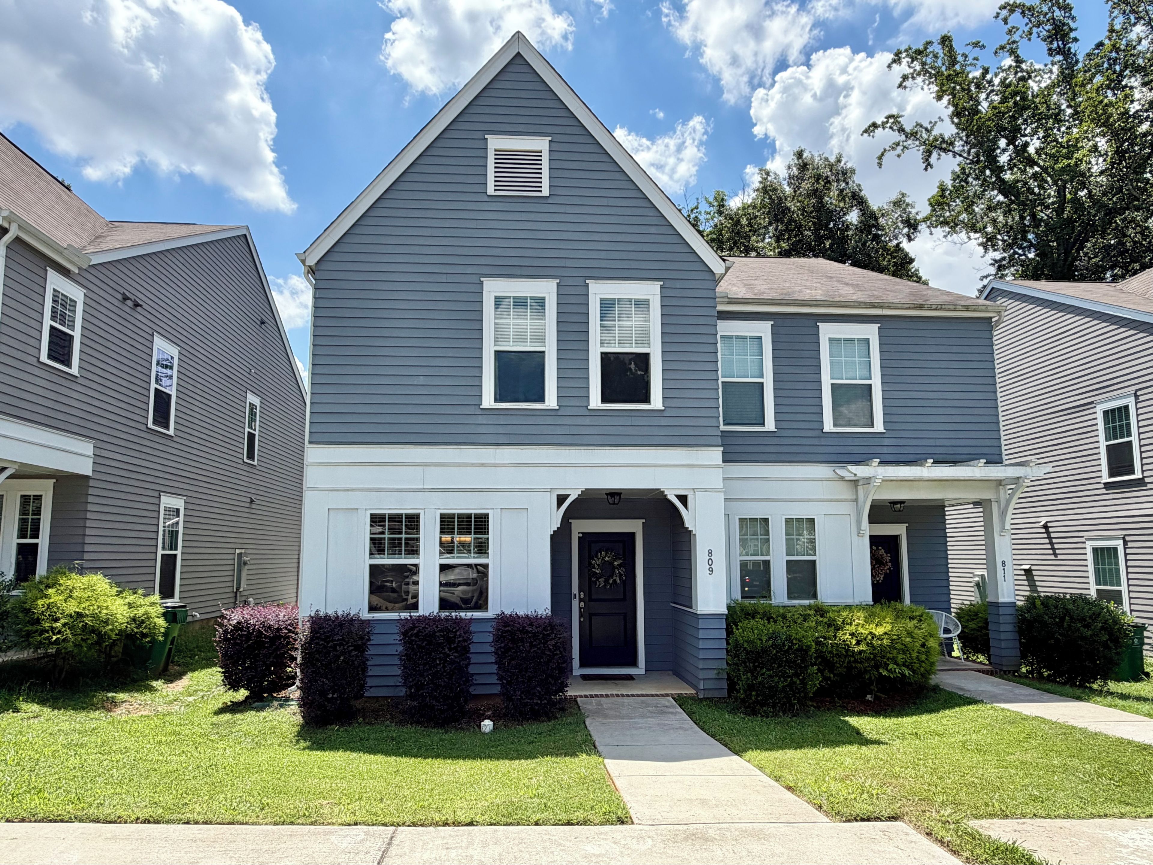 A two-story residential building with a central entrance, a covered porch, and a visible address number.