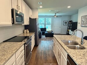 A kitchen with granite countertops, stainless steel appliances, and a view to the living area. - Fully Furnished Retreat In The Heart Of Charlotte (Charlotte)