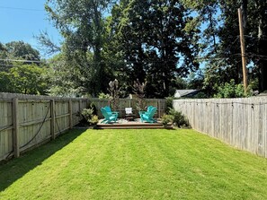 A backyard with a wooden fence, two turquoise chairs, and a small table. - Fully Furnished Retreat In The Heart Of Charlotte (Charlotte)