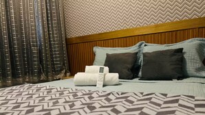 A hotel room with a bed, pillows, a headboard, a patterned bedspread, and a wall with a herringbone design. - 402 Functional and Welcoming. (Belém)