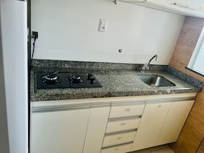 A kitchen with a granite countertop, a gas stove, a sink, and white cabinetry. - 402 Functional and Welcoming. (Belém)