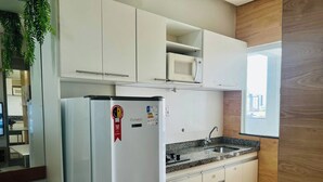 A compact kitchen with white cabinetry, a built-in microwave, and a stainless steel sink. - 402 Functional and Welcoming. (Belém)