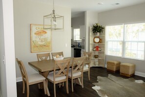 A dining area with a wooden table and chairs, a hanging light fixture, and a wall-mounted picture. - Brand-New Family-Friendly Home 5 Minutes to USC & Downtown (Cayce)