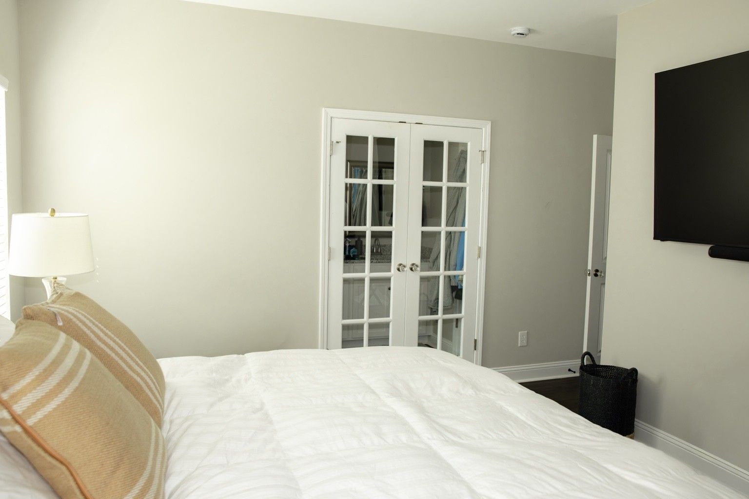A hotel room with a bed, a lamp, a television, and a wardrobe.
