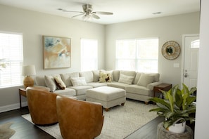 A living room with a sectional sofa, two armchairs, a coffee table, a floor lamp, and a ceiling fan. - Brand-New Family-Friendly Home 5 Minutes to USC & Downtown (Cayce)