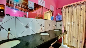 Een badkamer met een roze muur, een zwart-wit schaakbordvloer en een glazen wastafel.