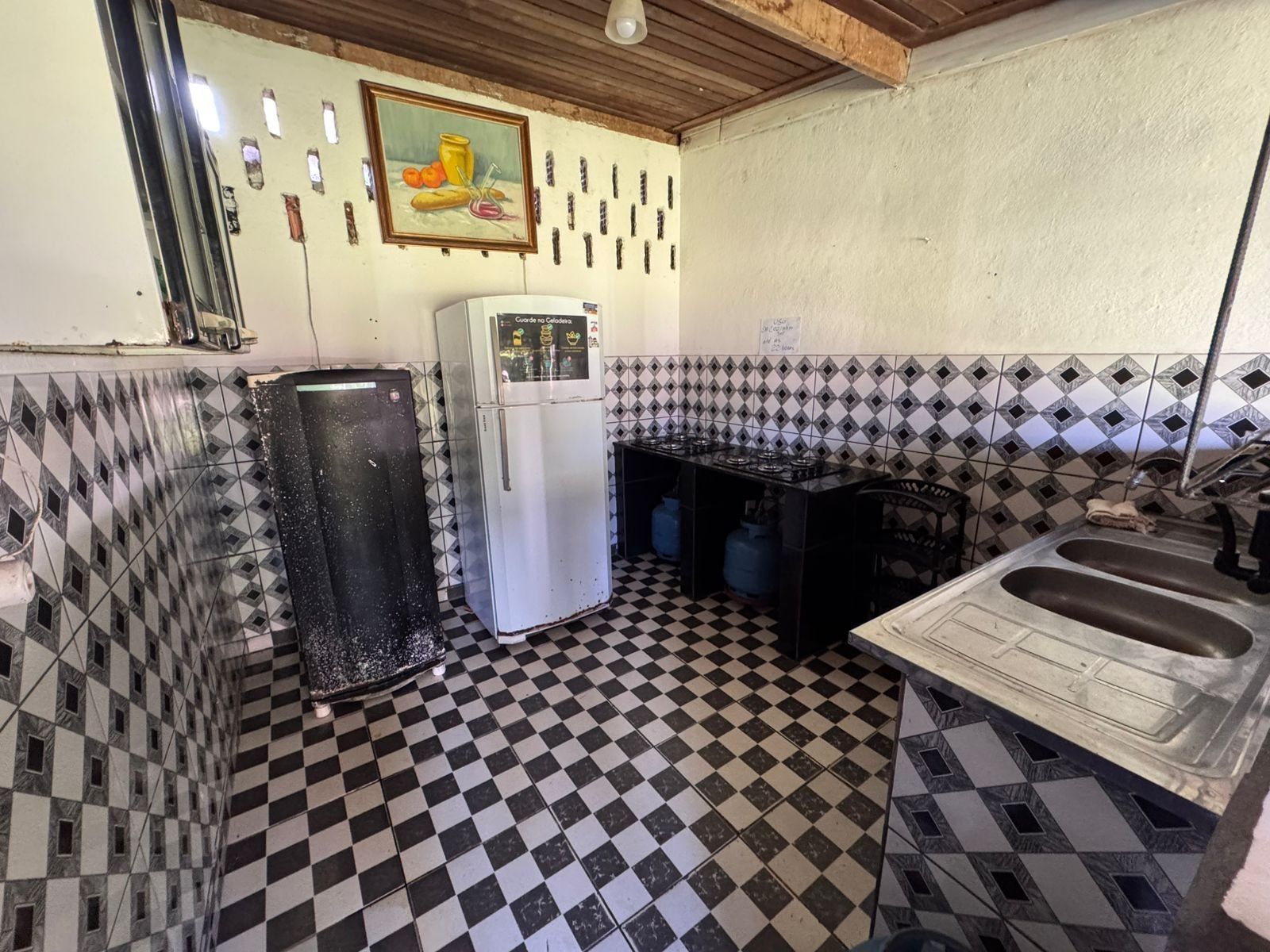 Una cocina con refrigerador, pileta y piso de cerámica.