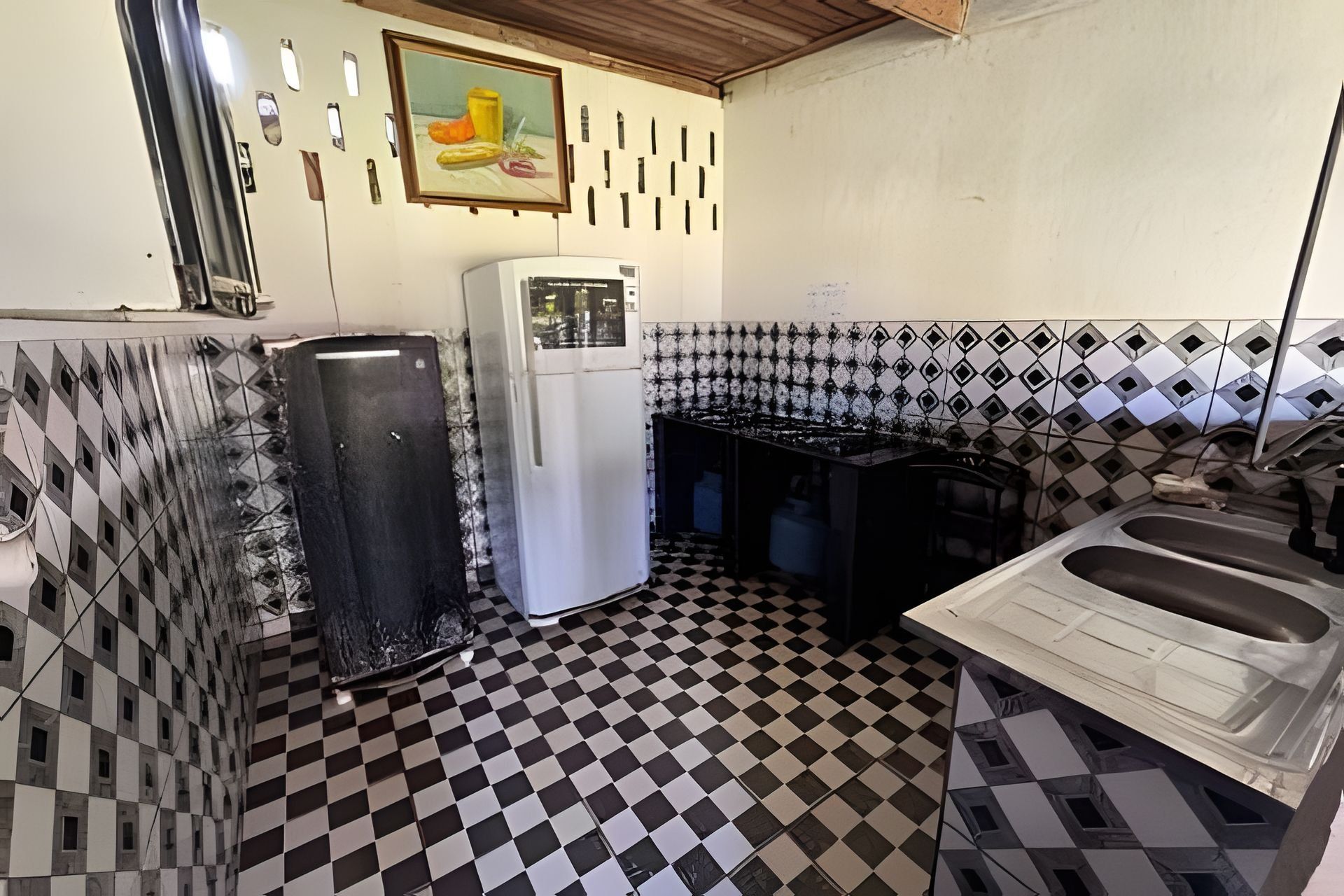 A compact kitchen with a refrigerator, sink, and tiled backsplash.