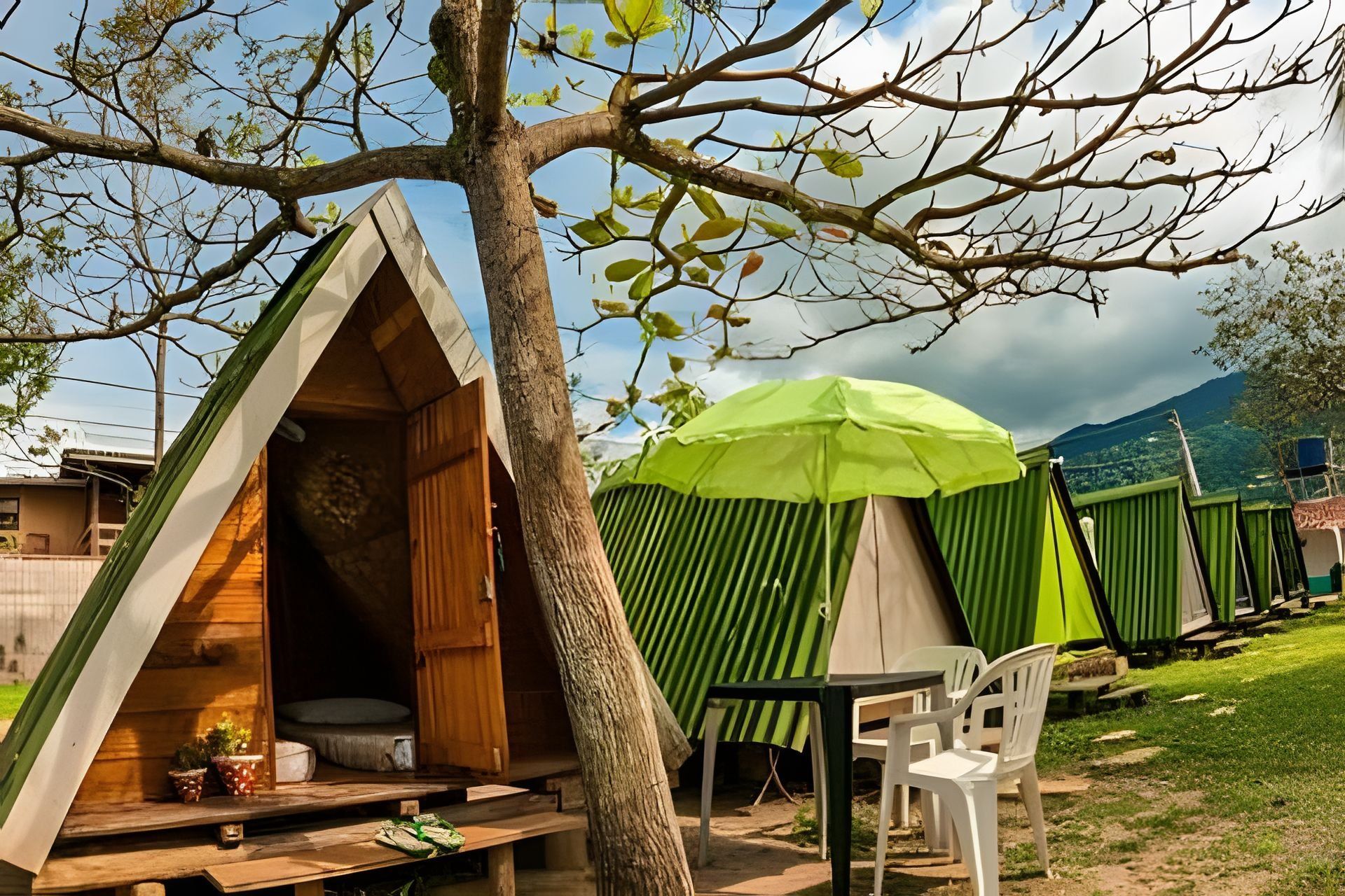 Una casa en el árbol con interior de madera, un paraguas verde y una mesa con sillas.