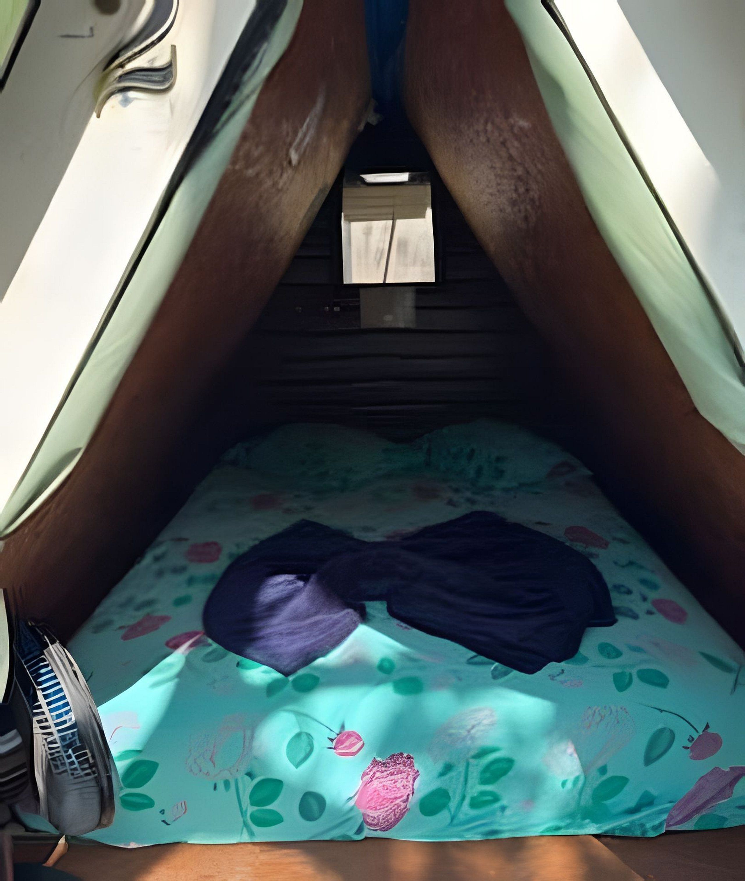A tent with a bed inside, a small table, and a pair of shoes.