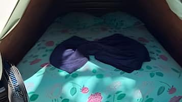 Een tent met een bed, een kleine tafel en een paar schoenen.