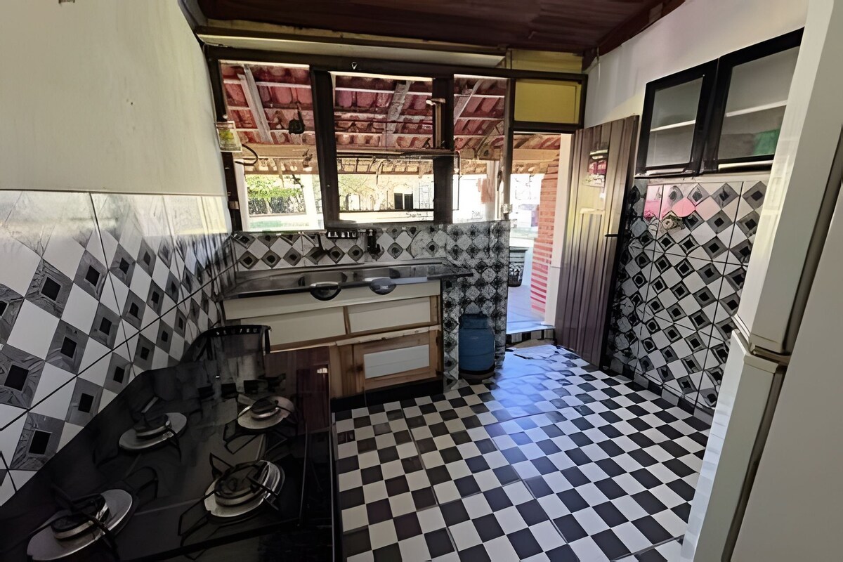 Una cocina compacta con piso a cuadros, una estufa a gas y una ventana con vista a la calle.
