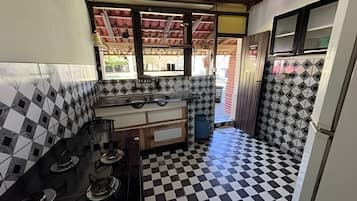 A compact kitchen with a checkered floor, a gas stove, and a window overlooking a street.