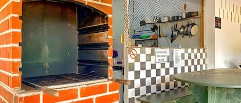 A brick oven with a checkered backsplash and a metal table.
