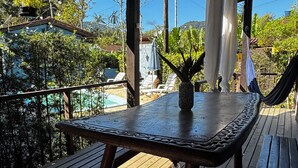 A wooden deck with a table and benches, overlooking a pool and greenery. - Vrbo Property (São Sebastião)
