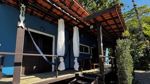 A wooden deck with a hammock, a covered porch with a tiled roof, and a small garden area with a tree. - Vrbo Property (São Sebastião)
