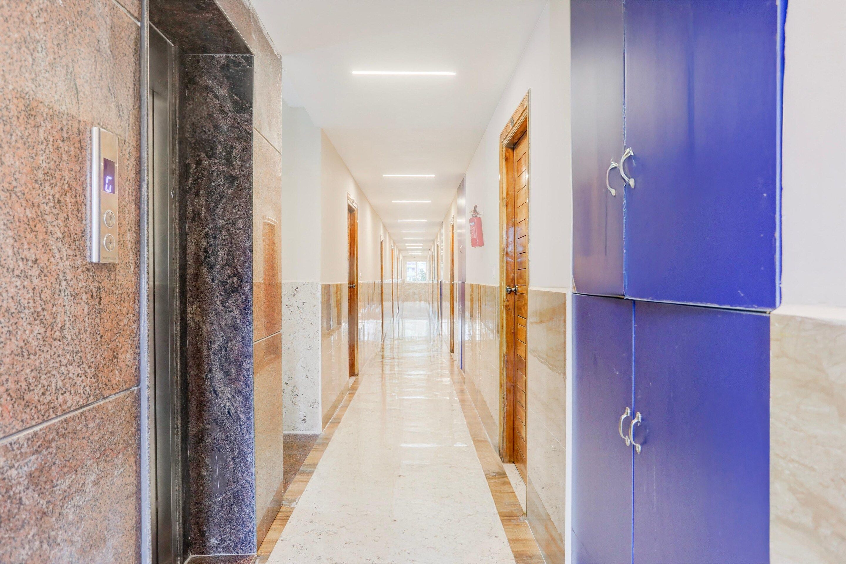 A corridor with a marble floor, doors, and a blue wall.