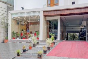 A hotel entrance with a red carpet, potted plants, and a modern glass facade. - Premium Hotel Rama Grand (Tirupati)