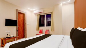 Una camera d'albergo con un letto, una televisione, una macchina per il caffè e una finestra con tende.