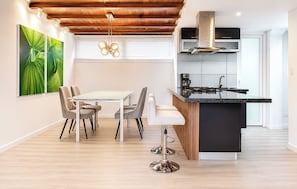 A modern kitchen with a central island, a dining area with a glass table, and a ceiling with exposed wooden beams. - Apartamento Premium con terraza, a pasos de la Zona t/Parque 93/area 120 mts (Bogotá, D.C.)