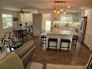 Eine moderne Küche mit einer zentralen Kochinsel, Barhocker und einem Essbereich mit einer Couch und Stühlen.