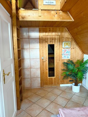 A wooden interior with a door, a shelf unit, a potted plant, and a poster on the wall. - A small house with a sauna, nestled in the apple orchard of the Altes Land region near Hamburg (Hollern-Twielenfleth)