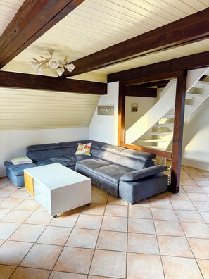 A living room with a sectional sofa, a coffee table, and a staircase. - A small house with a sauna, nestled in the apple orchard of the Altes Land region near Hamburg (Hollern-Twielenfleth)