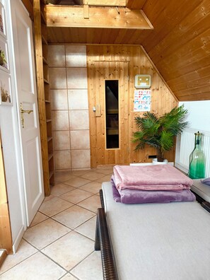 Ein Zimmer mit Holzbalkendecke, einem Bett mit gefalteten Handtüchern, einer Topfpflanze und einer an der Wand befestigten Infotafel.