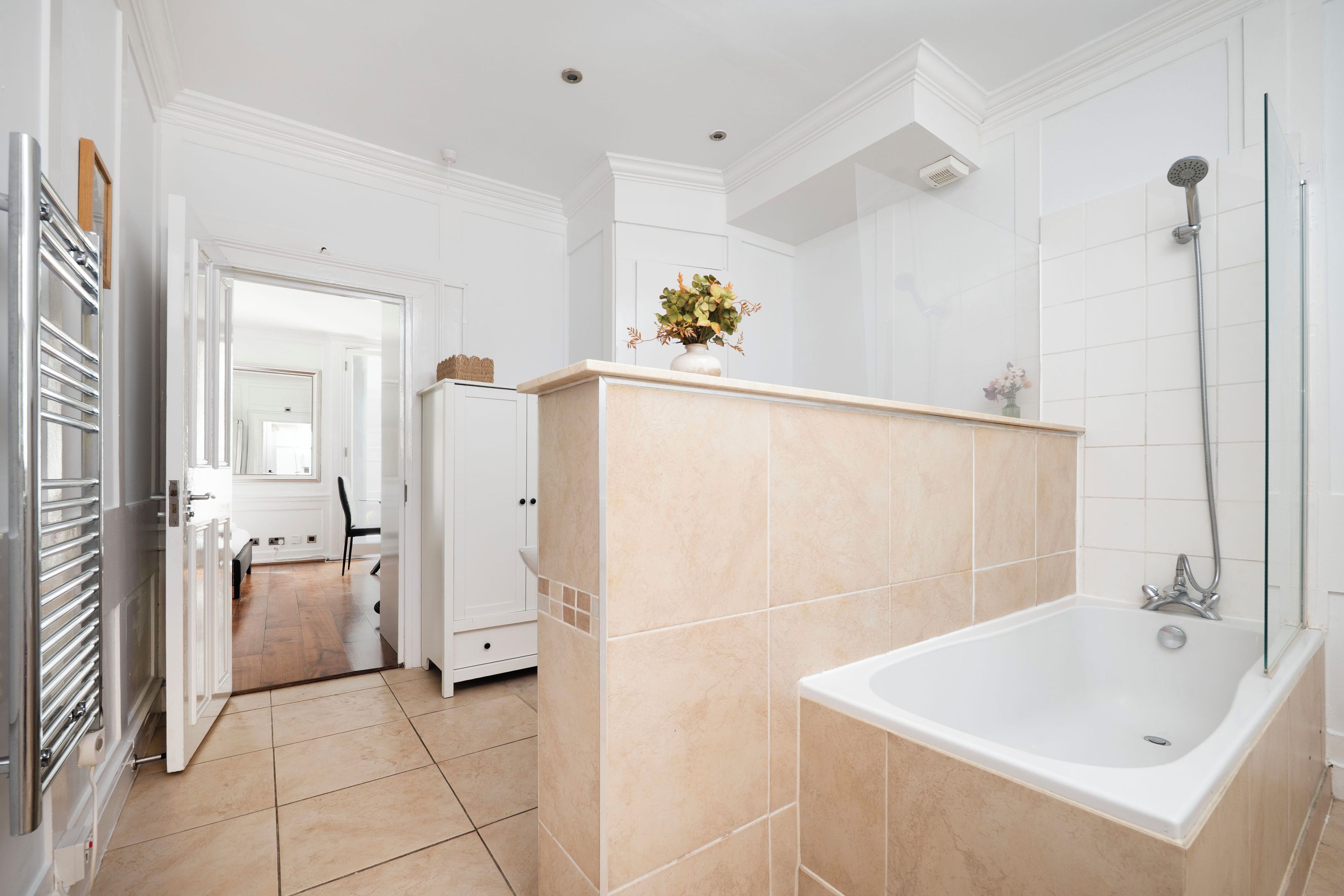A modern bathroom with a bathtub, a shower, and a toilet. There is a small plant on the counter.
