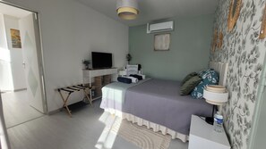 Un dormitorio con una cama, un escritorio, un televisor y una ventana.