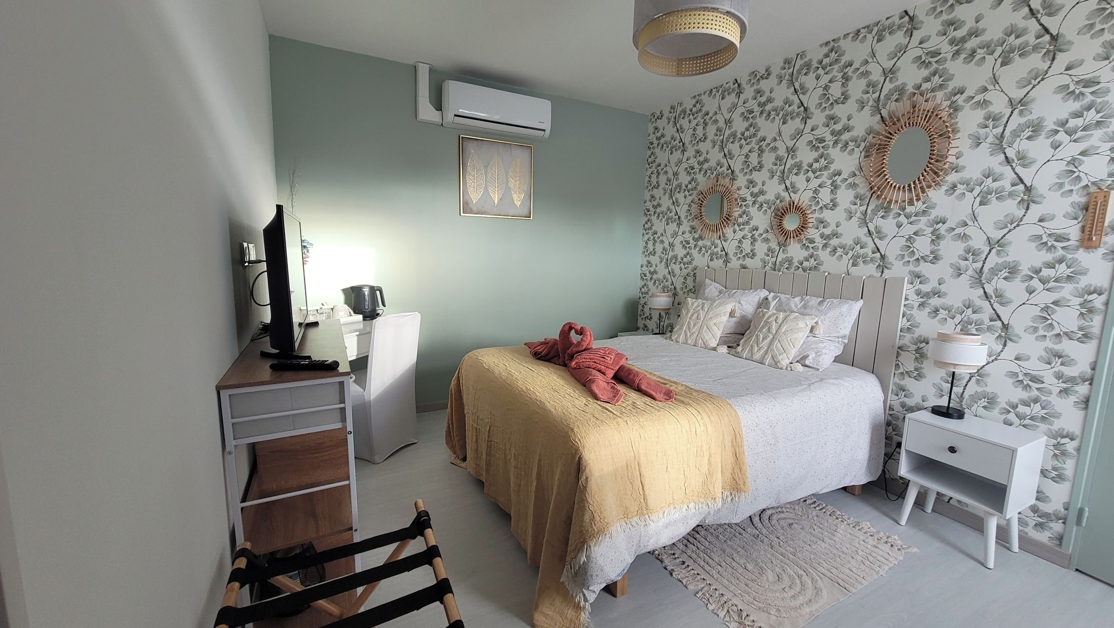 A bedroom with a bed, bedside tables, a desk, an air conditioner, and a chair.
