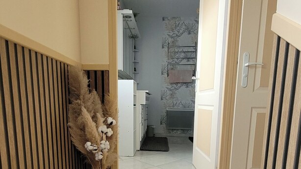 Un pasillo con suelo de madera que conduce a una habitación con radiador y perchero.