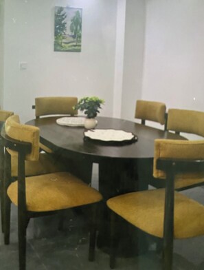 Una sala conferenze con un tavolo rotondo, quattro sedie, una pianta in vaso e un quadro appeso al muro.