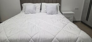 A neatly made bed with a white quilt and two pillows. - Spacious 3-bedroom 3full baths  apartment in serene Nairobi with fitness!! (Nairobi)