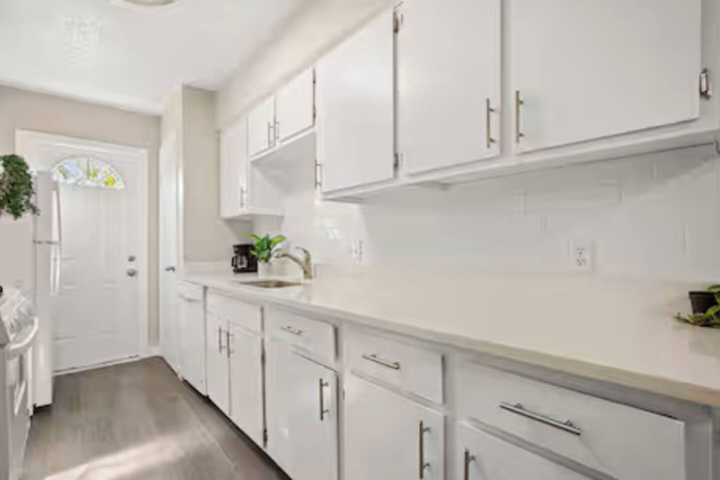 A modern kitchen with white cabinetry, a countertop, and a sink.