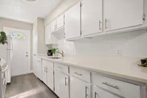 A modern kitchen with white cabinetry, a countertop, and a sink.