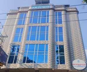 A building with a sign reading 'SN.TOWER' and another sign indicating 'KGMT Outreach Clinic'. - Deluxe Room Hotel Nirvis Grand (Guwahati)
