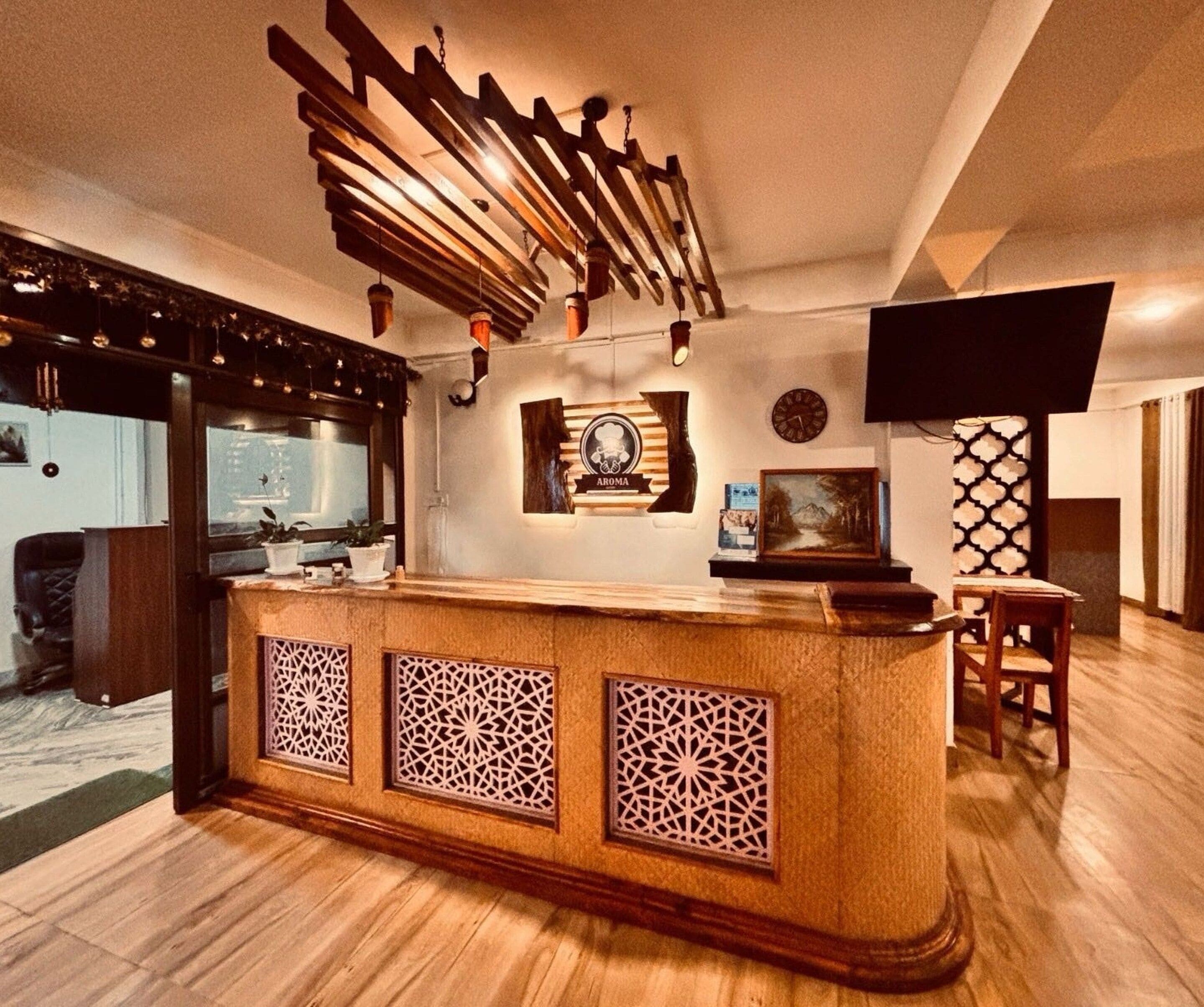 A reception area with a wooden counter, decorative wall panels, a clock, and a television mounted on the wall.
