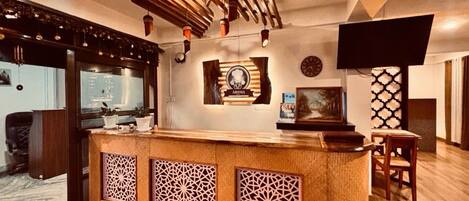 A reception area with a wooden counter, decorative wall panels, a clock, and a television mounted on the wall.