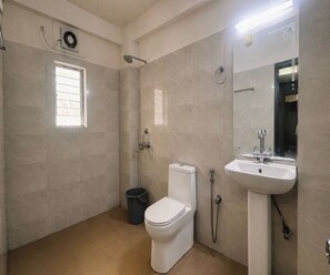 A bathroom with a toilet, sink, and shower. - Deluxe Room Hotel Nirvis Grand (Guwahati)