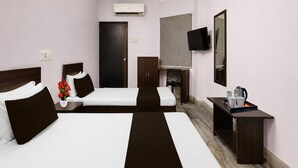 Een hotelkamer met twee bedden, een bureau, een stoel, een televisie en een airconditioning.