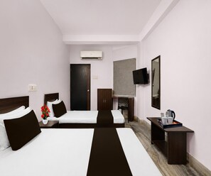A hotel room with two beds, a desk, a chair, a TV, and an air conditioning unit. - Deluxe Room Shree Ram Residency (Cuttack)