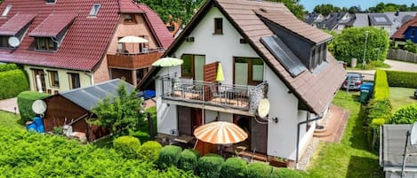 A residential house with a balcony, solar panels, and a well-maintained garden.