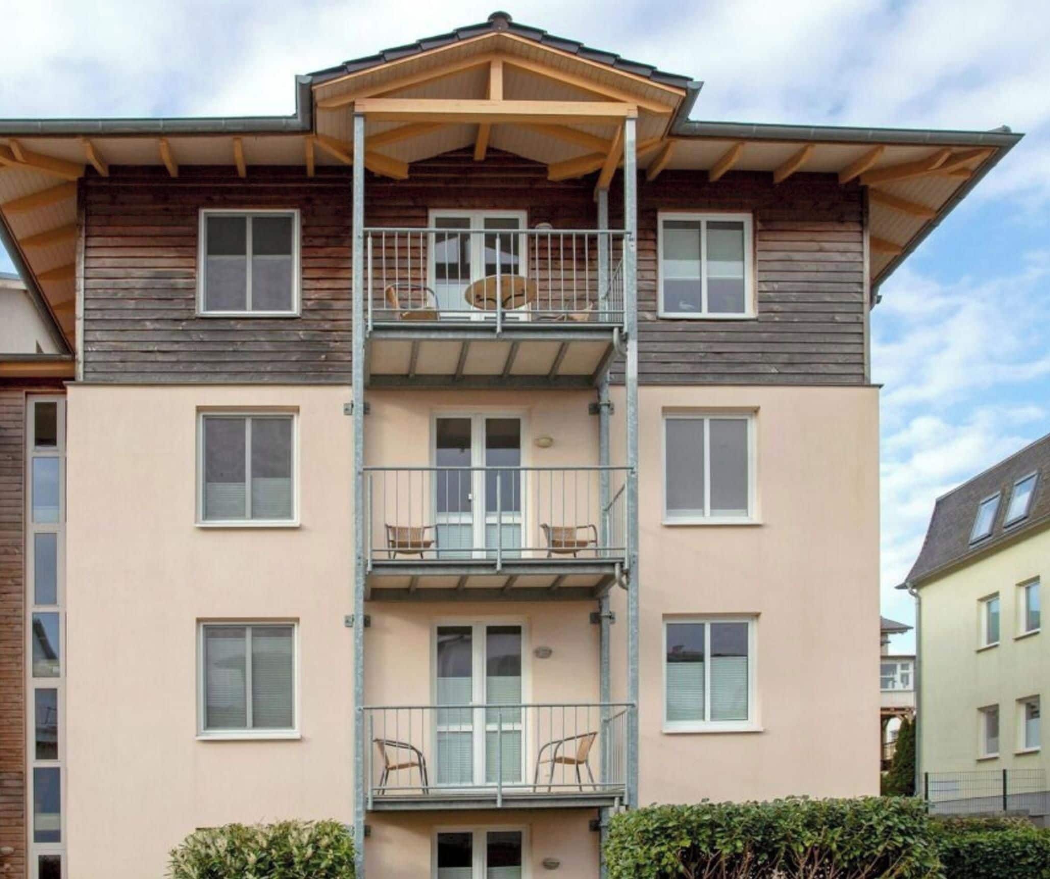 Ein mehrgeschossiges Wohngebäude mit einem zentralen Atrium, Balkonen und einer flachen Dachterrasse.