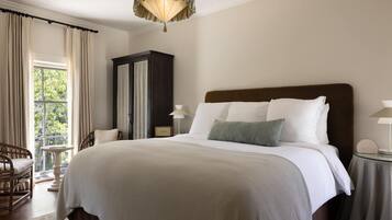 A hotel room with a large bed, a nightstand, a chair, a wardrobe, and a window with curtains.